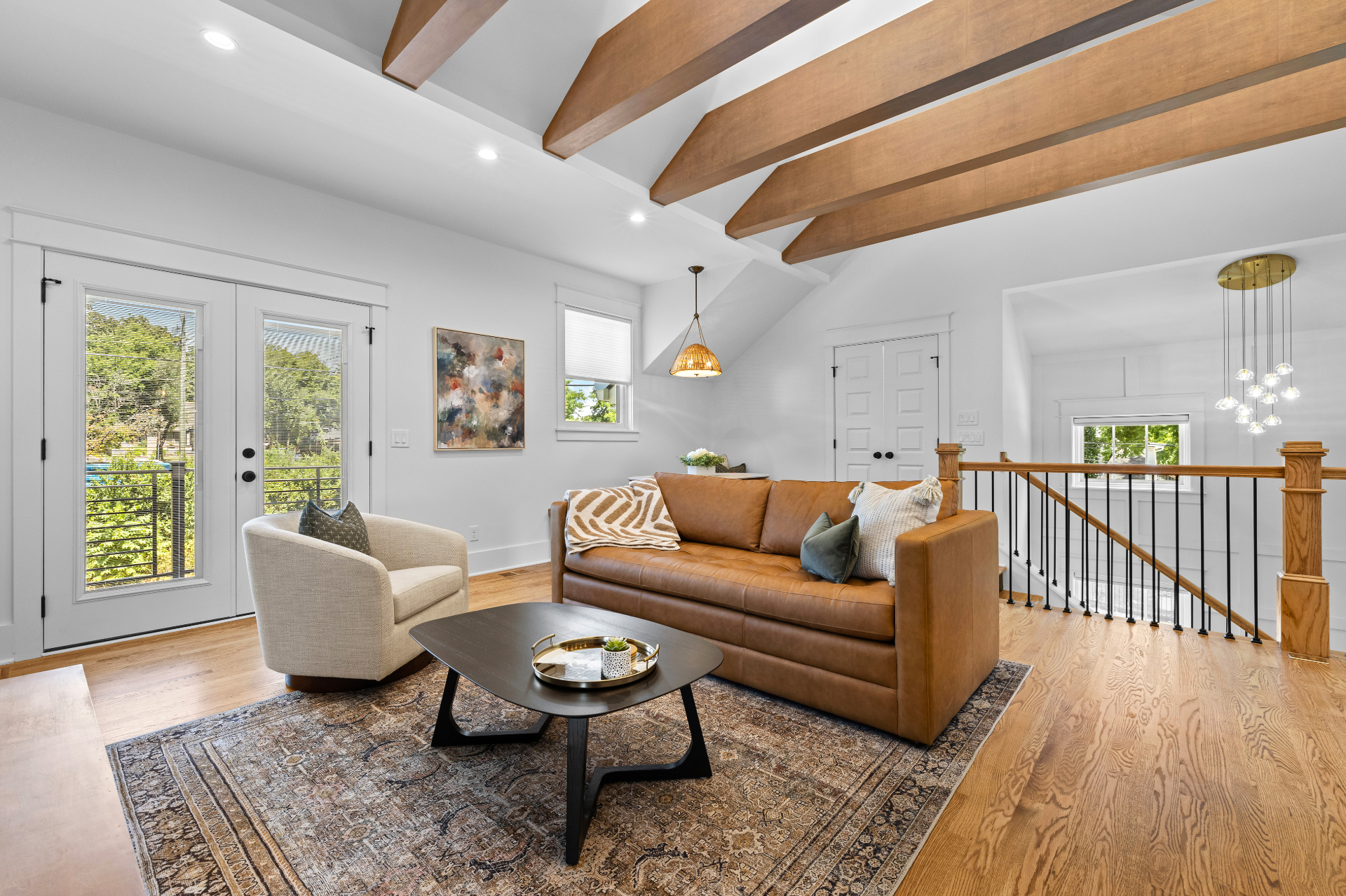 Bright living room with vaulted beams, fireplace, and leather sofa
