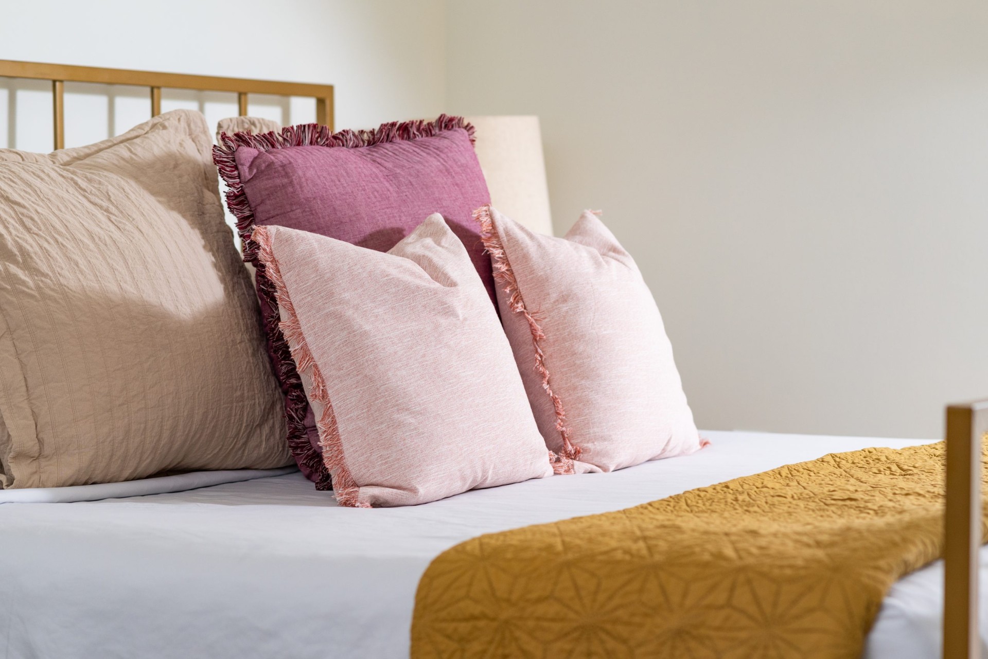 Layered bedding with fringe pillows and a mustard throw in a one-bedroom Nashville short-term rental