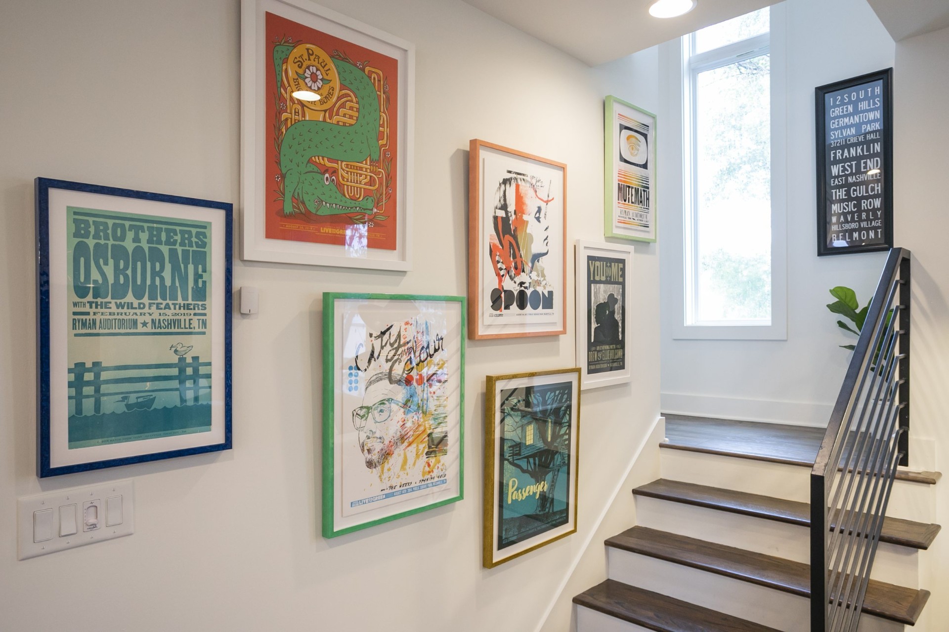 Gallery wall of framed Nashville concert posters in a two-bedroom townhome short-term rental stairwell